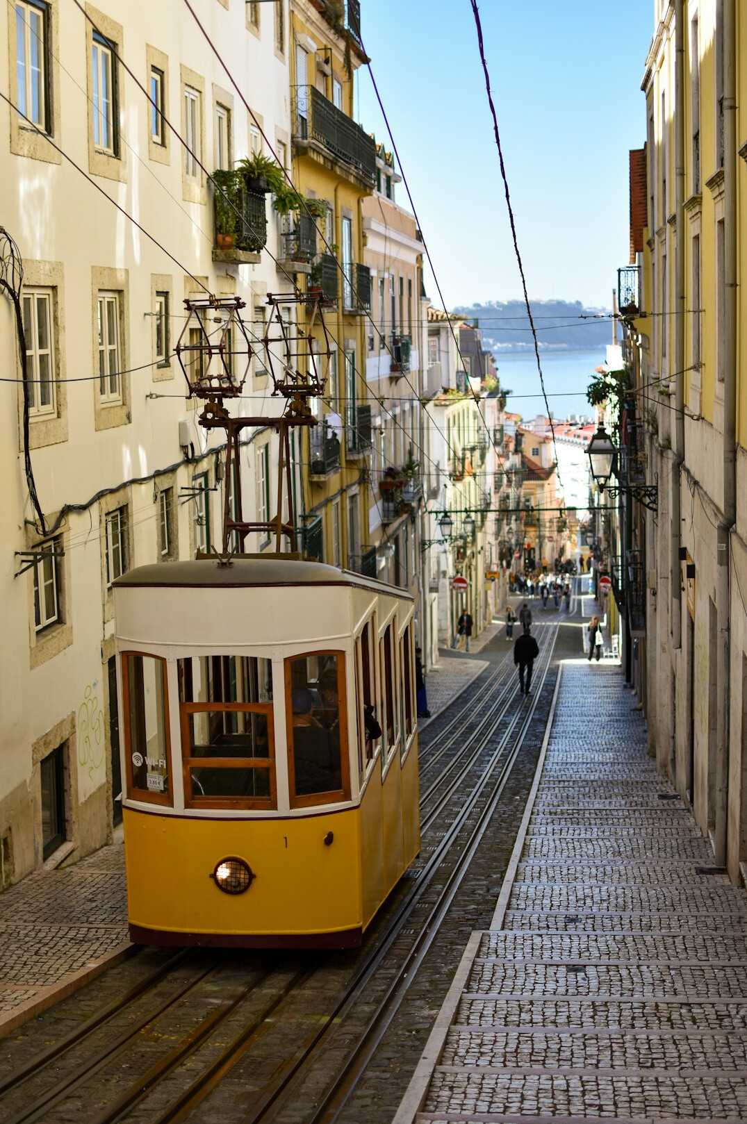 Yellow tram on a narrow street between old apartment buildings in Lisbon